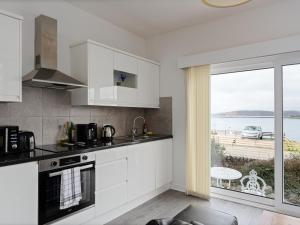 Eine Küche mit weißen Schränken und Meerblick in der Unterkunft Ards House in Oban + 48 Fotos