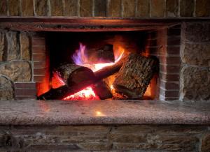 a brick fireplace filled with fire and logs at Pierian Chalets by TETOS - Grand in Velventós