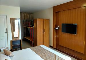 a bedroom with a bed and a cabinet with a television at Drizzle Drop Inn in Ooty +288 photos