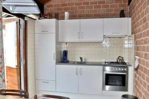 a kitchen with white cabinets and a sink at Boerenslag 46 in Sint Maartenszee
