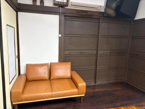 a brown leather couch in a room with a tv at 指宿古民家宿 in Ibusuki