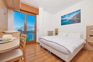 a bedroom with a bed and a table and a desk at Beach Hotel Rosa in Malcesine +45 photos