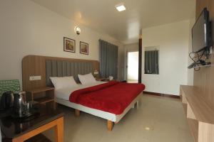 a bedroom with a large bed with a red blanket at Drizzle Drop Inn in Ooty