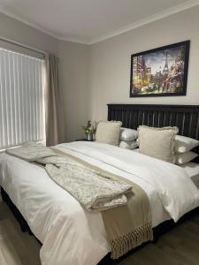 a bedroom with a large white bed with a picture on the wall at Beachside Bliss Strand in Strand