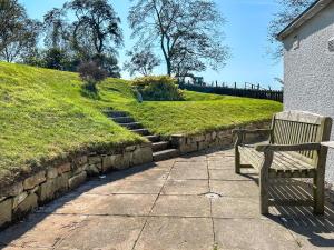 a bench sitting on a sidewalk next to a grassy hill at Rosscot in Ankerville