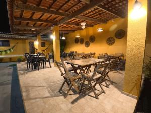 a restaurant with wooden tables and chairs in a room at Pousada pôr do sol in Riachuelo