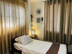 a bedroom with a bed and a window with a clock on the wall at Anton and Isabel Bangued- 2BR for 5 in Bangued