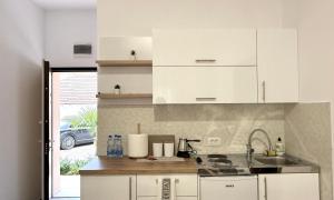 a kitchen with white cabinets and a sink at Nanchev Apartments in Gevgelija