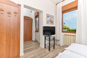 a room with a tv and a bed and a window at Beach Hotel Rosa in Malcesine