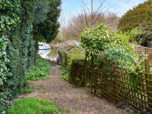 a garden path with a fence next to a canal at Riverside Retreat in Beccles
