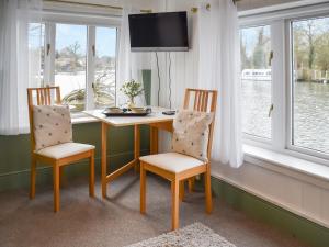 a table and two chairs in a room with windows at Riverside Retreat in Beccles
