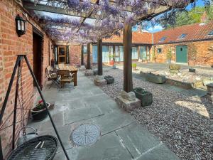 an outdoor patio with a pergola with purple flowers at Meadow View Broadlea in Stokeham