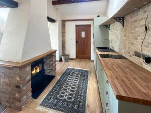a kitchen with a stone fireplace in the middle at Meadow View Broadlea in Stokeham