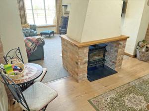 a living room with a brick fireplace and a table at Meadow View Broadlea in Stokeham +9 photos