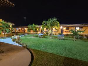 a building with a yard with palm trees at night at Pousada pôr do sol in Riachuelo