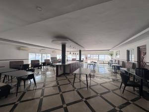 a dining room with tables and chairs and windows at Hotel Izzy Stay in Maputo