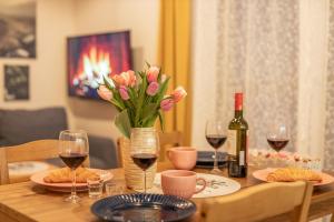 a table with a vase of flowers and wine glasses at Villa Kasztelan Apartamenty in Ustrzyki Dolne