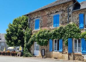an old brick building with blue windows and tables at chambre dhote condat sur ganaveix in Condat-sur-Ganaveix