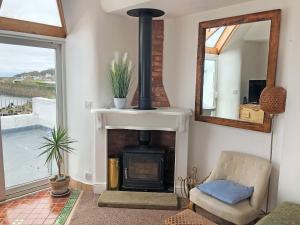 a living room with a fireplace and a mirror at Hen Joppa in Newlyn