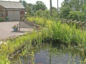a bench sitting next to a pond in a garden at Rundales Cottage in Appleby