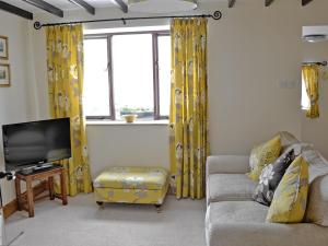 a living room with yellow curtains and a couch and a tv at Rundales Cottage in Appleby