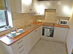 a kitchen with white cabinets and a sink at Rundales Cottage in Appleby