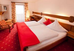 a hotel room with a large bed with red and white sheets at Landhotel-Gasthof-Schreiner in Hohenau