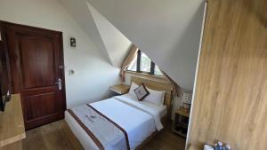 a small bedroom with a bed and a window at Vô Tư Luxury Hotel in Da Lat