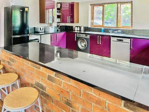 a kitchen with purple cabinets and a brick wall at Grantham House in Grantham