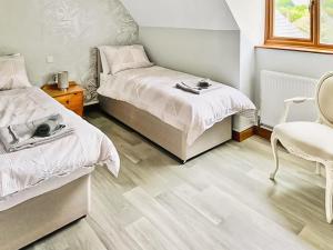 a bedroom with two beds and a chair at Grantham House in Grantham