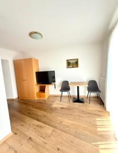 a room with a table and two chairs and a television at Garni Hotel Dorothea in Tirolo