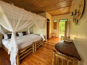 a bedroom with a bed with a canopy at Kibale Riverside Camp in Kamwenge