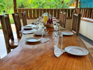 a wooden table with plates and glasses on it at Kibale Riverside Camp in Kamwenge