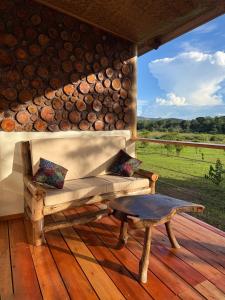 a living room with a couch and a table on a deck at Kibale Riverside Camp in Kamwenge +8 photos