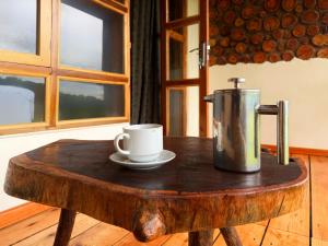 a coffee pot and a cup on a wooden table at Kibale Riverside Camp in Kamwenge