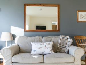a living room with a couch and a mirror at Cow Pasture Cottage in Hallington