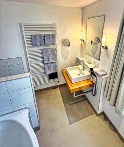 a bathroom with a tub and a sink and a mirror at Parkhotel Steimker Berg Wolfsburg in Wolfsburg +39 photos