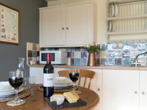 a table with a bottle of wine and two glasses at Cow Pasture Cottage in Hallington
