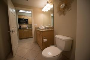 
a bathroom with a toilet, sink, and mirror at Escapes! To The Shores Orange Beach, A Ramada by Wyndham in Orange Beach
