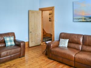 a living room with two leather couches and a mirror at Longsands Retreat in Tynemouth