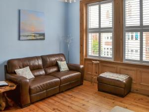 a living room with a brown leather couch and a stool at Longsands Retreat in Tynemouth