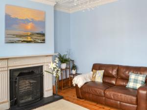 a living room with a leather couch and a fireplace at Longsands Retreat in Tynemouth