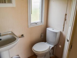 a bathroom with a toilet and a sink and a window at Praise Machine Caravan Experience in Jaywick Sands