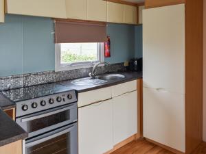 a kitchen with a sink and a stove at Praise Machine Caravan Experience in Jaywick Sands