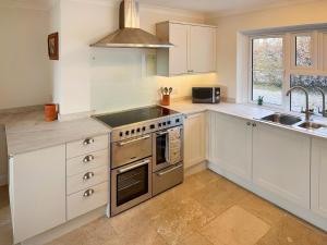 a kitchen with white cabinets and a stove top oven at Rosemeade in Hessett