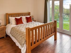a bedroom with a wooden bed with red pillows at Rosemeade in Hessett