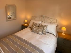 a bedroom with a white bed with pillows and two lamps at Rosemeade in Hessett +2 photos