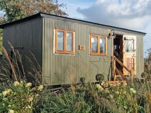a green tiny house sitting in a field at Bailey Huts in Litton