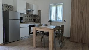 a kitchen with a wooden table with chairs and a refrigerator at AURA MARINA - Guest House Fiumicino in Fiumicino