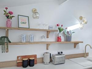 a kitchen counter with wooden shelves on the wall at Longshore in Runswick +12 photos